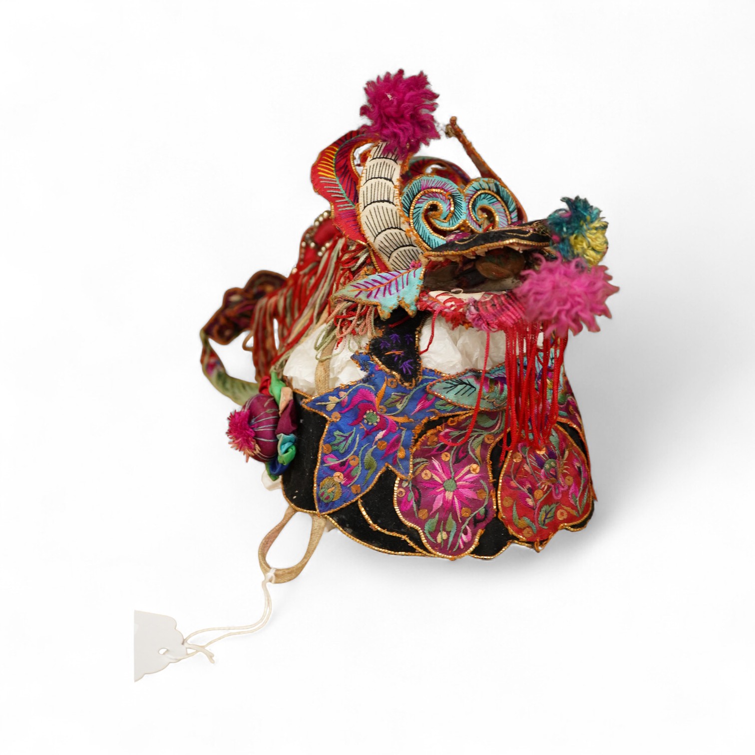 A decorative Chinese child’s festival ‘dragon’ hat, decorated with embroidered panels, tasselling and pom-poms with an elaborate dragon face and head dress. 20cm high. Condition - tasselling is missing around the dragons